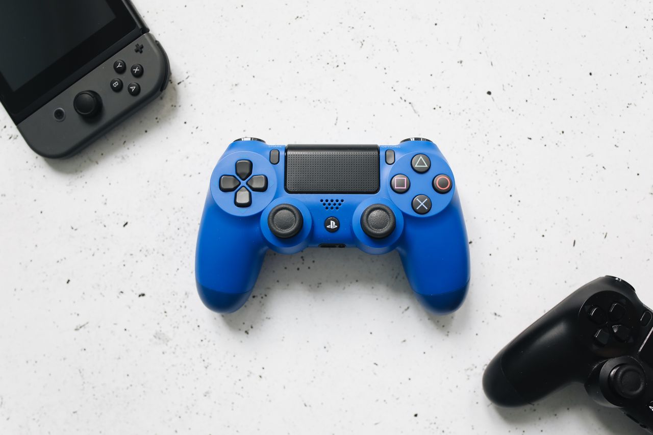 A top view of various colorful gaming controllers on a white surface.